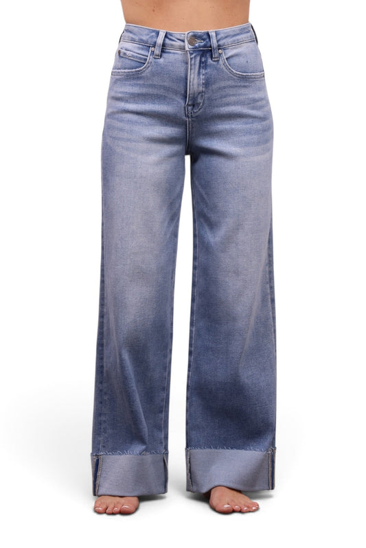 A model wearing light blue wide-leg jeans with a faded wash and rolled cuffs, paired with a light pink off-the-shoulder crop top, shown against a plain white background.
