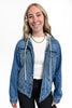 Woman wearing a blue denim jacket over a white shirt on a white background