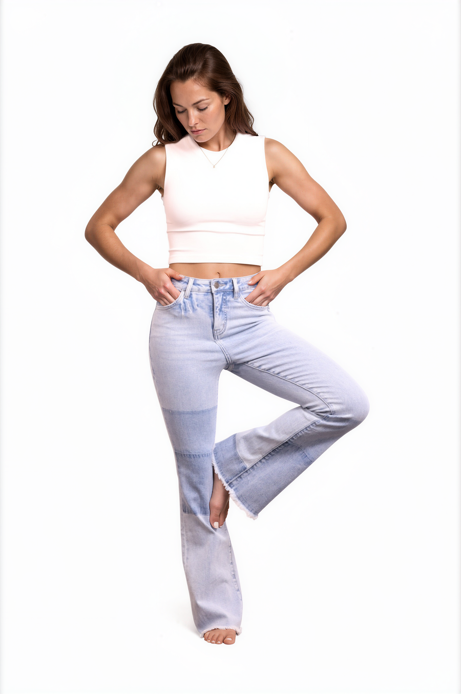 Woman wearing light blue jeans and a white sleeveless top on a white background