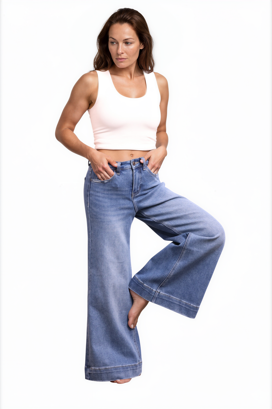 Woman wearing a white tank top and blue jeans on a white background
