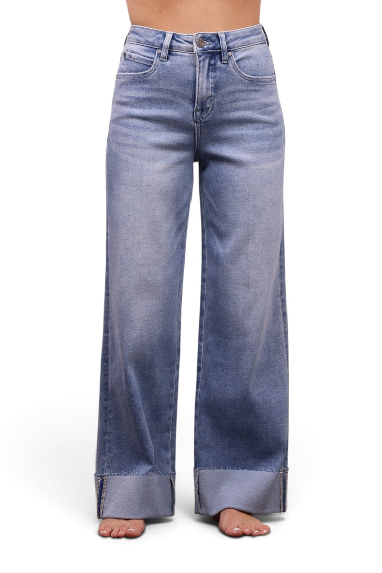 A model wearing light blue wide-leg jeans with a faded wash and rolled cuffs, paired with a light pink off-the-shoulder crop top, shown against a plain white background.