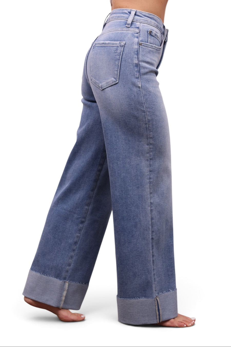 A person shown from the waist down wearing light blue wide-leg jeans with rolled cuffs, photographed against a plain white studio background.