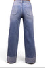 A person shown from the back wearing light blue wide-leg jeans with rolled cuffs and a light beige cropped top, photographed against a plain white studio background.