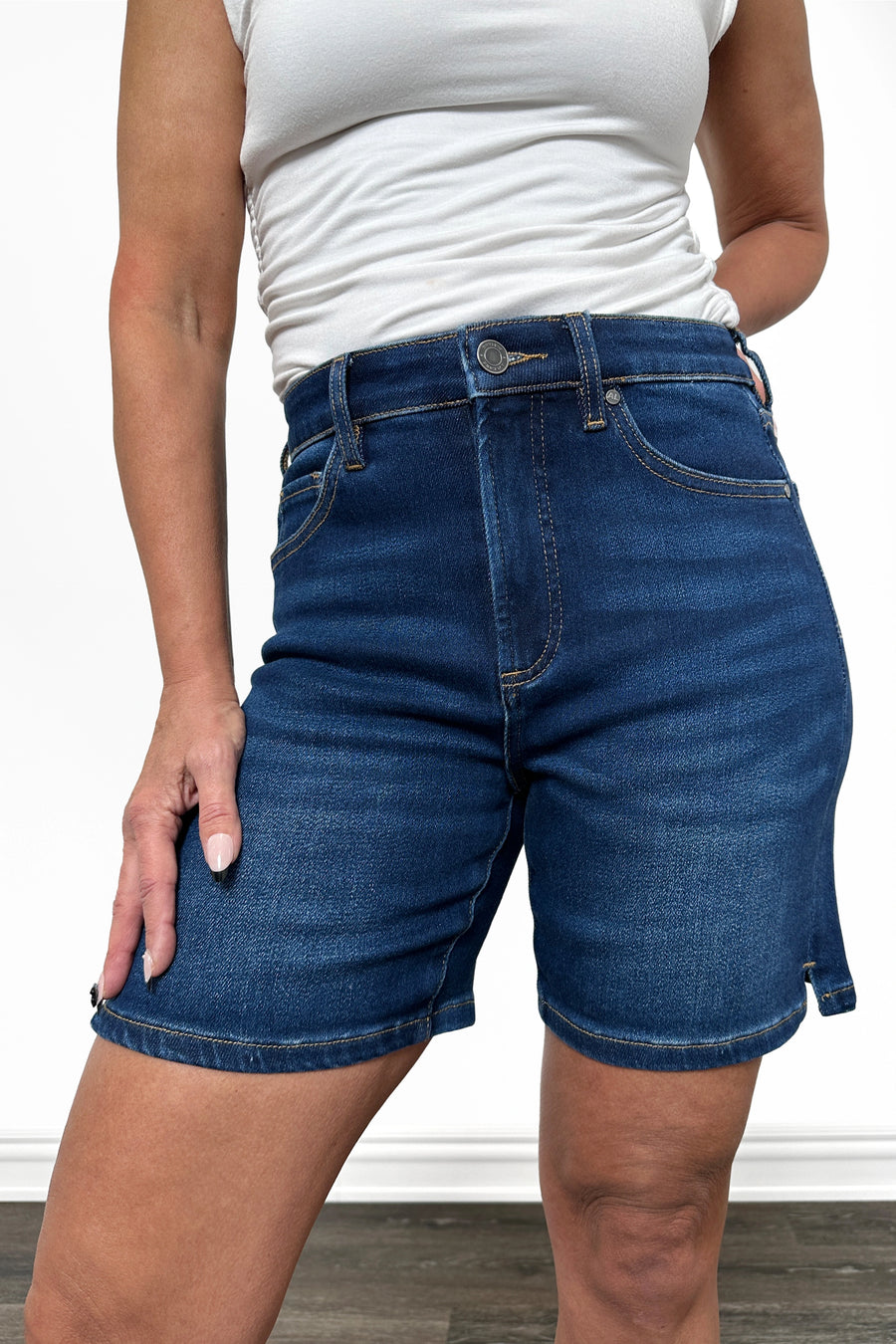 Person wearing blue denim shorts and a white top on a plain background