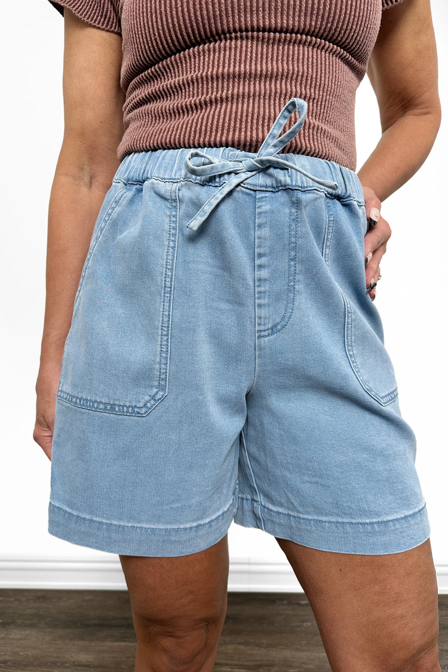 Light blue denim shorts worn by a person on a neutral background