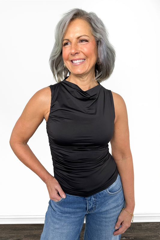 Woman wearing a black sleeveless top and blue jeans on a white background