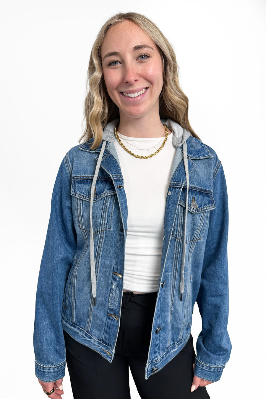 Woman wearing a blue denim jacket over a white shirt on a white background