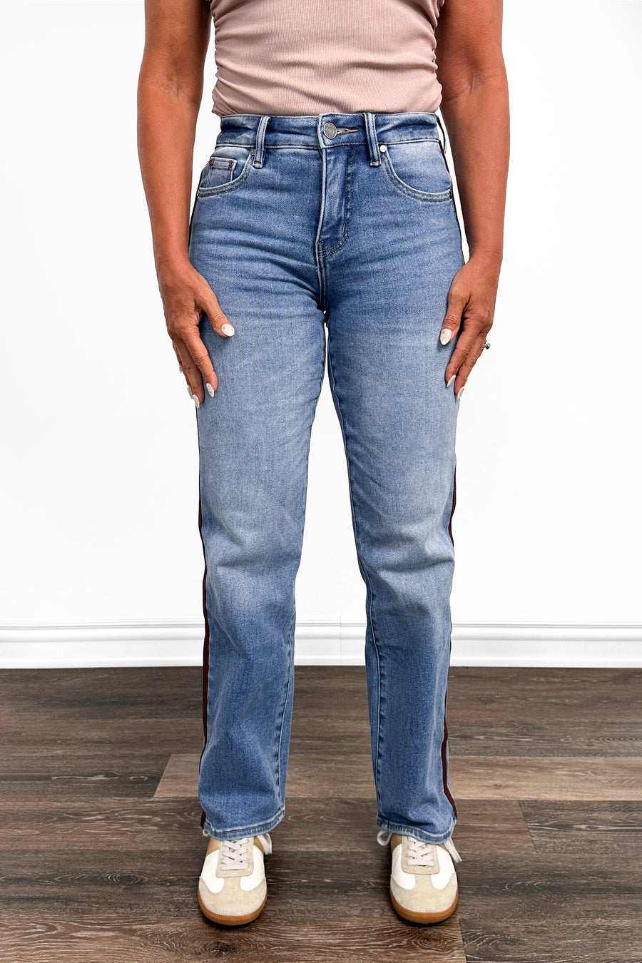 Person wearing blue jeans and a beige top on a wooden floor.