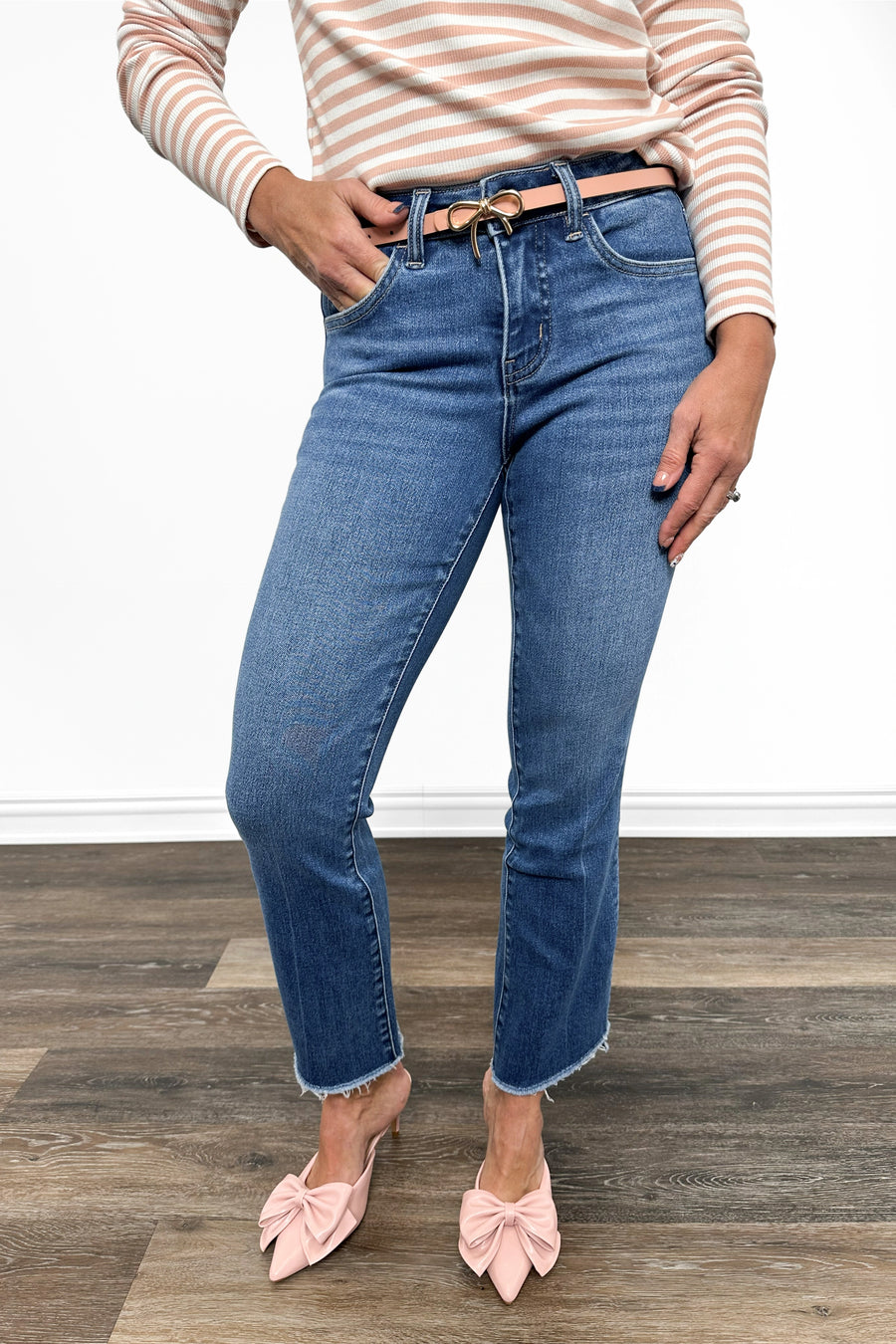 Person wearing blue jeans and a striped shirt on a wooden floor.
