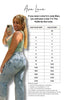 Woman taking a selfie wearing a green top and blue jeans with a size chart for Ava Lane clothing on a white background.