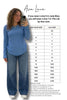 Woman taking a selfie wearing a blue top and jeans with a size chart for Ava Lane clothing.