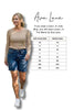 Woman wearing a striped sweater and denim shorts with a size chart for Ava Lane clothing.
