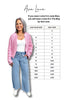 Woman wearing a pink cardigan and blue jeans with a size chart for Ava Lane clothing.
