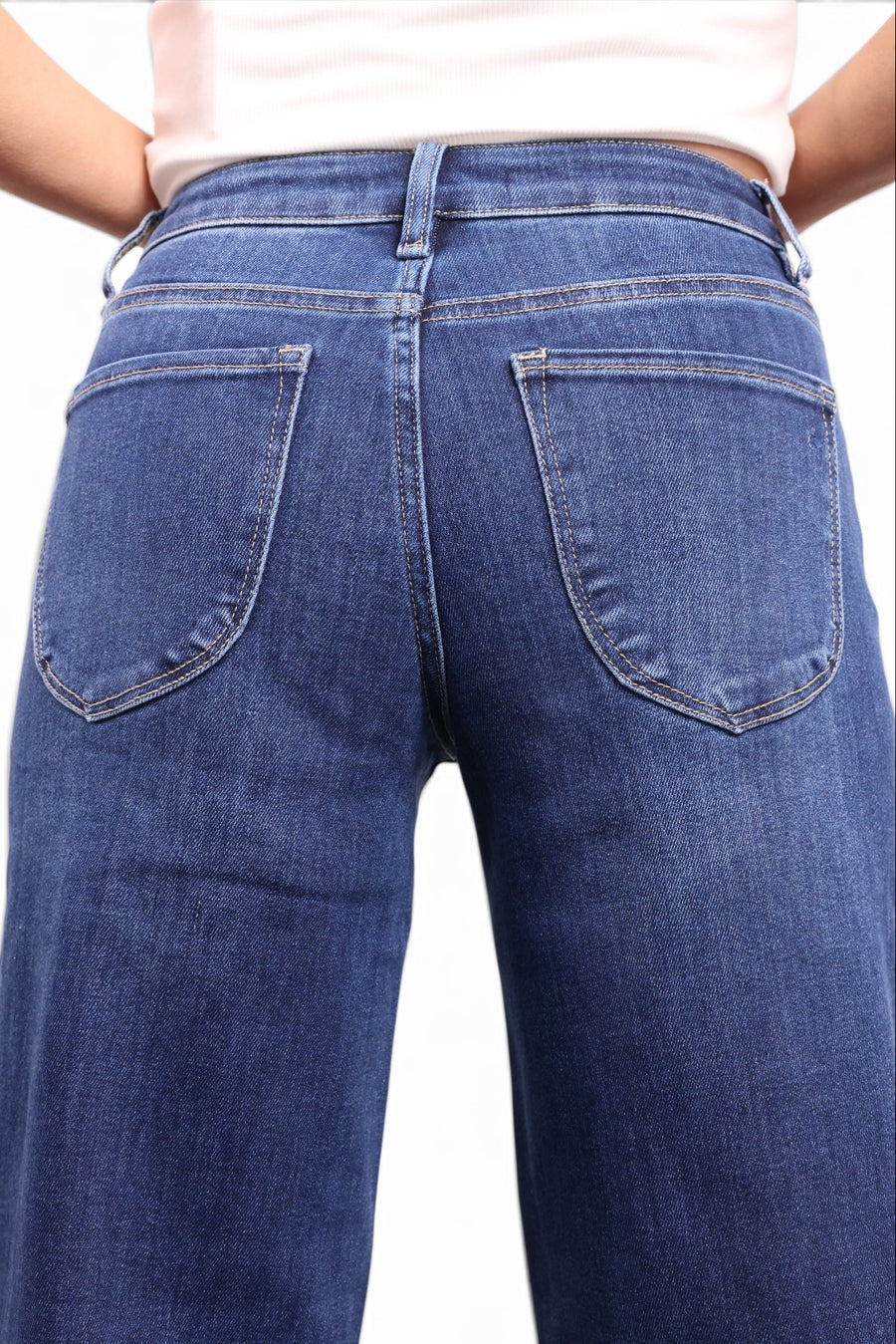 Rear view of a person wearing blue denim jeans with a light pink top, shown against a plain white background.