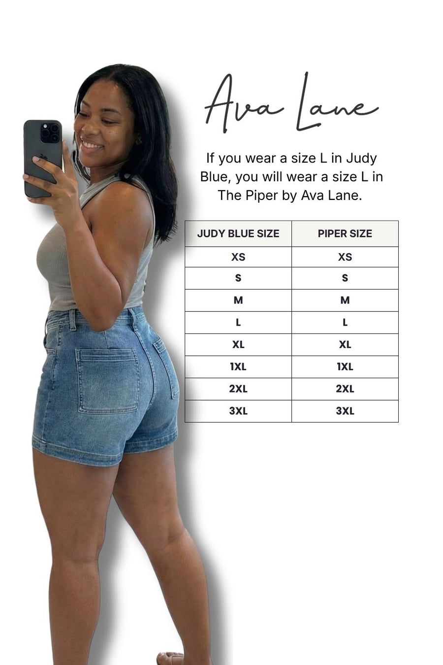 Woman taking a selfie wearing denim shorts with a size chart for Ava Lane clothing brand.