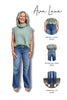 Woman wearing a green sleeveless top and blue jeans with text describing the clothing brand and features.