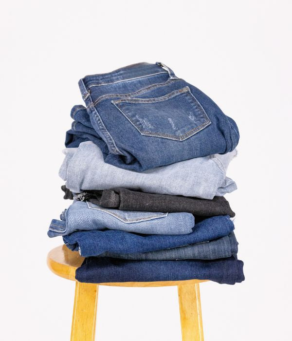 A stack of folded Ava Lane jeans in light, medium and dark washes